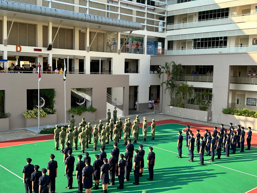 Uniformed school cadets standing in formation blocks in the parade square for Speech Day."
